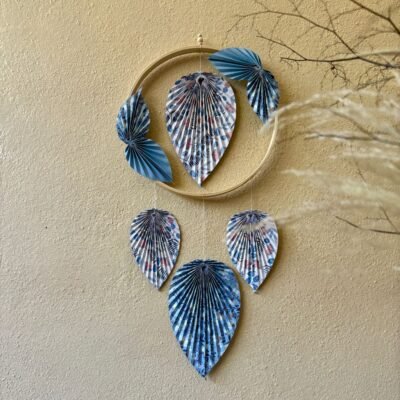 Un cercle en bambou de 15cm, ornée de pliage en origami en forme de feuille, une feuille se trouve dans le centre du cercle, quatre petites feuilles sont collées en diagonale sur le cercle, puis trois feuilles qui pendent le long du cercle. Les feuilles sont de couleurs bleues et blanches avec des motifs fleurit.
