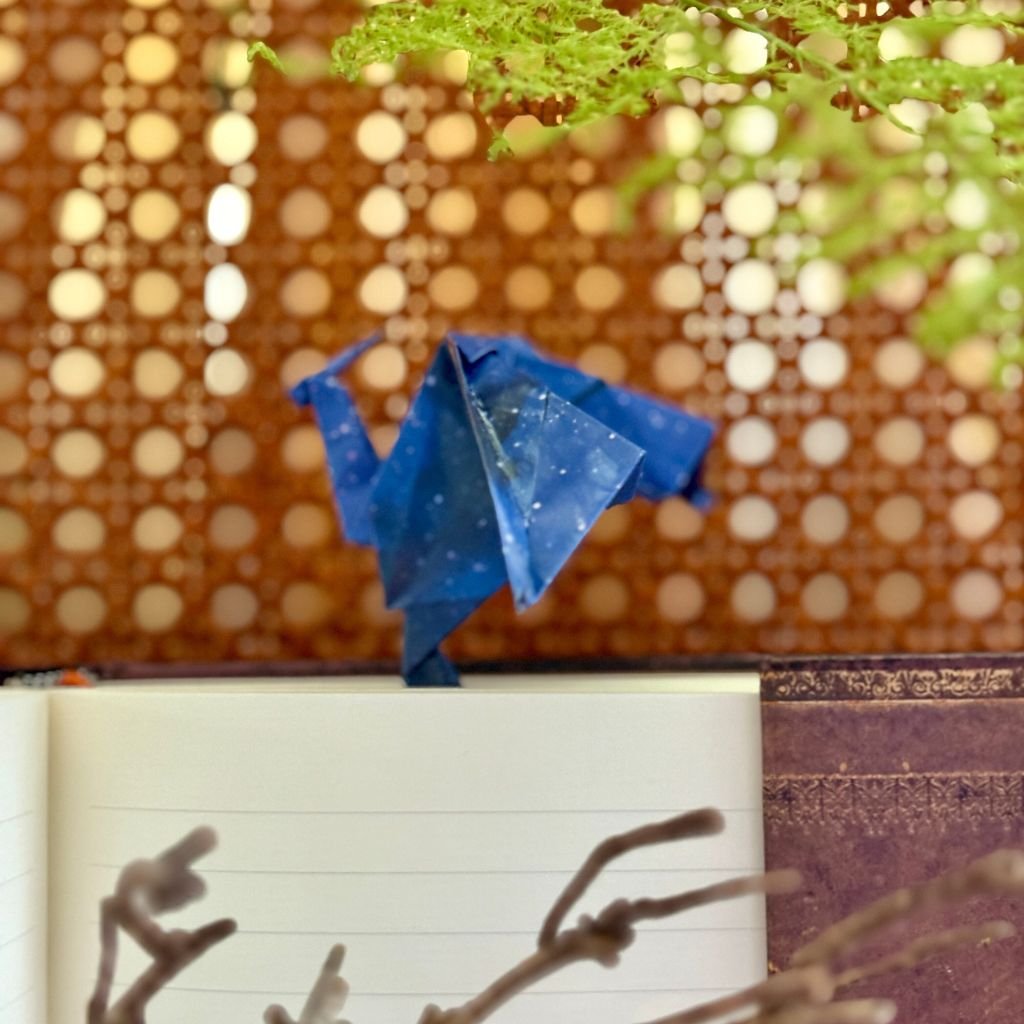 Un marque page en forme de dragon. Il se glisse entre les pages et le dragon se pose sur le haut du livre. Il est de couleur bleu/violet avec un style galaxie.