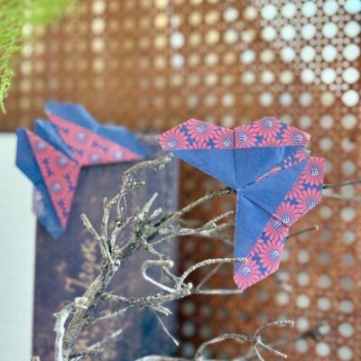 Deux marques pages en forme de papillons, qui se posent dans l'angle du livre. Les deux faces du papier apparaissent et sont inversé sur les deux papillons, soient du bleu sans motif, et du bleu avec des fleurs rouges.