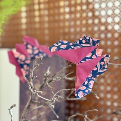 Deux marques pages en forme de papillons, qui se posent dans l'angle du livre. Les deux faces du papier apparaissent et sont inversé sur les deux papillons, soient du rouge bordeaux sans motif, et du bleu foncé avec des motifs fleurit rose.