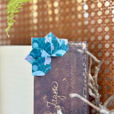 Un marque page en forme de lotus qui se pose dans l'angle du livre, de couleur bleu, avec des motifs de lotus, et de carpe koï bleu clair.