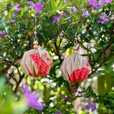 Des boucles d'oreilles avec des crochets simples en acier inoxydable, composées de deux petites perles en bois et d'un pliage en origami qui rappelle la forme des lanternes japonaise ronde ou d'une perle. Ces boucles d'oreilles sont dorée, rouge et orange avec des motifs dans le style japonais.