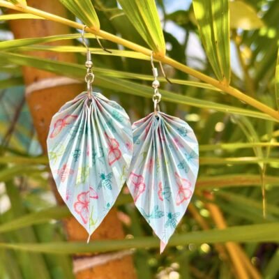 Boucle d'oreille en acier inoxydable argenté, avec un pliage en origami en forme de feuille. Les motifs du papier représentent des insectes dont des papillons, abeilles, libellules... La couleur dominante est bleu clair.