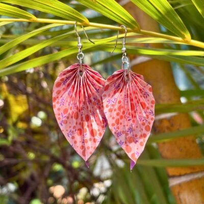 Boucle d'oreille en acier inoxydable argenté, avec un pliage en origami en forme de feuille. Les motifs du papier représentent des fleurs et petite feuilles. La couleur dominante est rose.